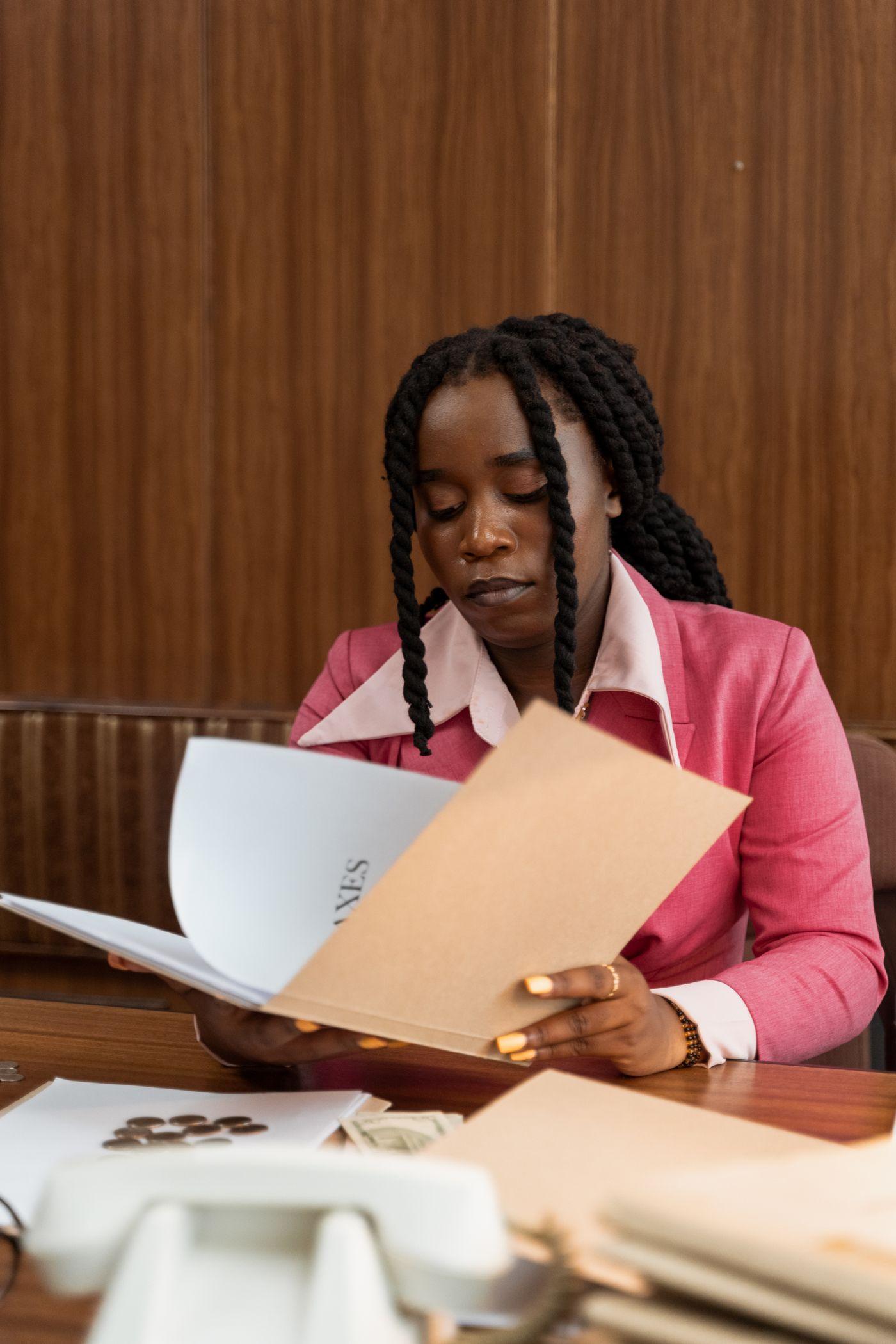 Black businesswoman in a pink jacket reviewing documents
